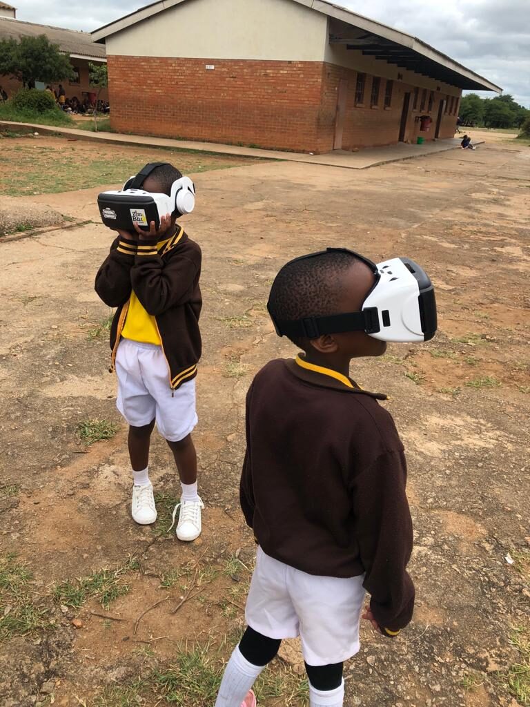 Two students wearing VR headsets outdoors at school